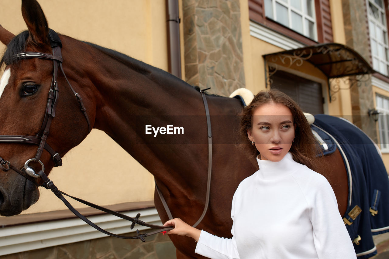 Young woman standing by horse