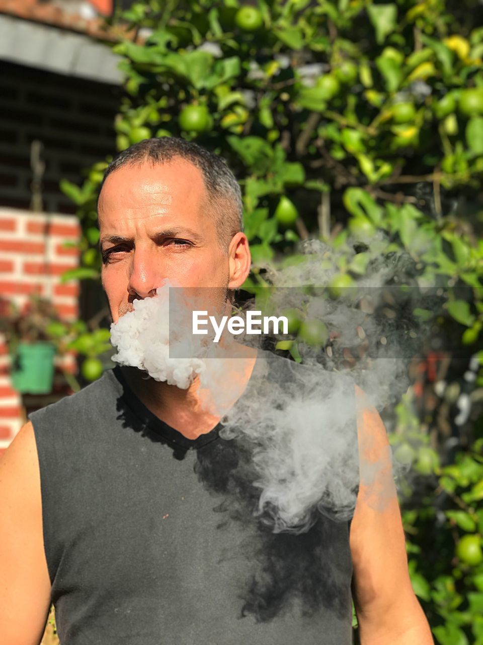 Portrait of man smoking against plants