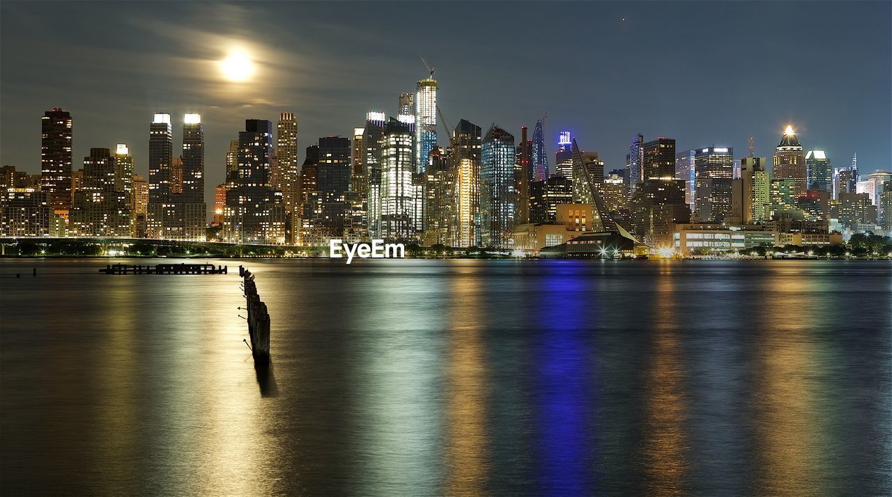 Illuminated buildings by river at night