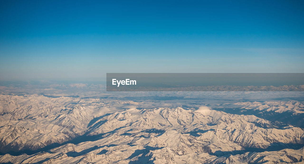 Scenic view of snowcapped mountains against blue sky