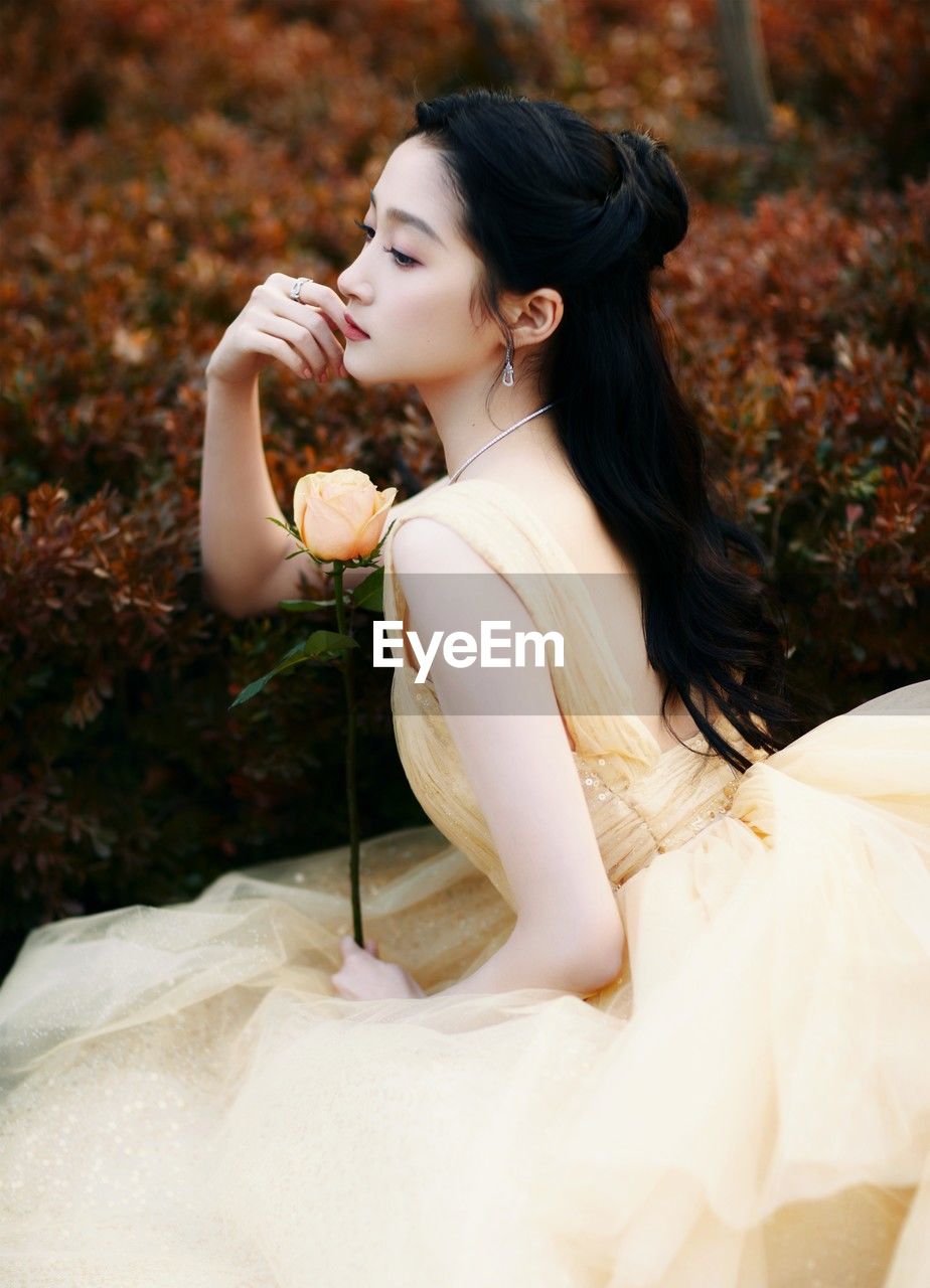 side view of young woman holding flower