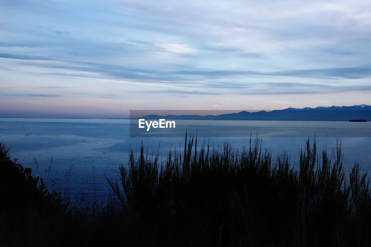 sky, water, beauty in nature, scenics - nature, reflection, tranquility, horizon, dawn, tranquil scene, cloud, morning, nature, lake, no people, sunrise, plant, environment, landscape, land, non-urban scene, idyllic, mountain, body of water, outdoors, beach, coast, ocean, travel destinations
