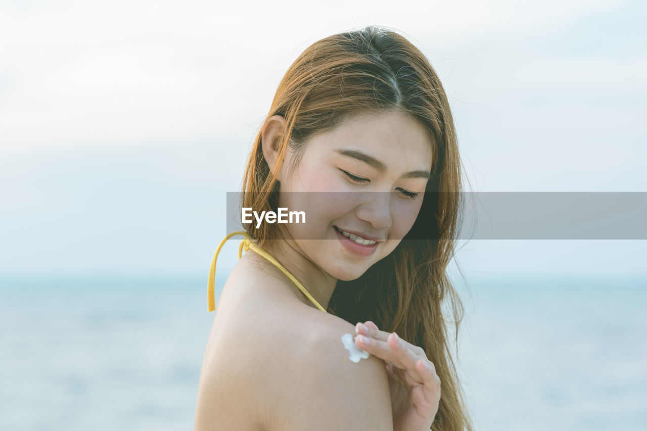 PORTRAIT OF SMILING WOMAN ON BEACH