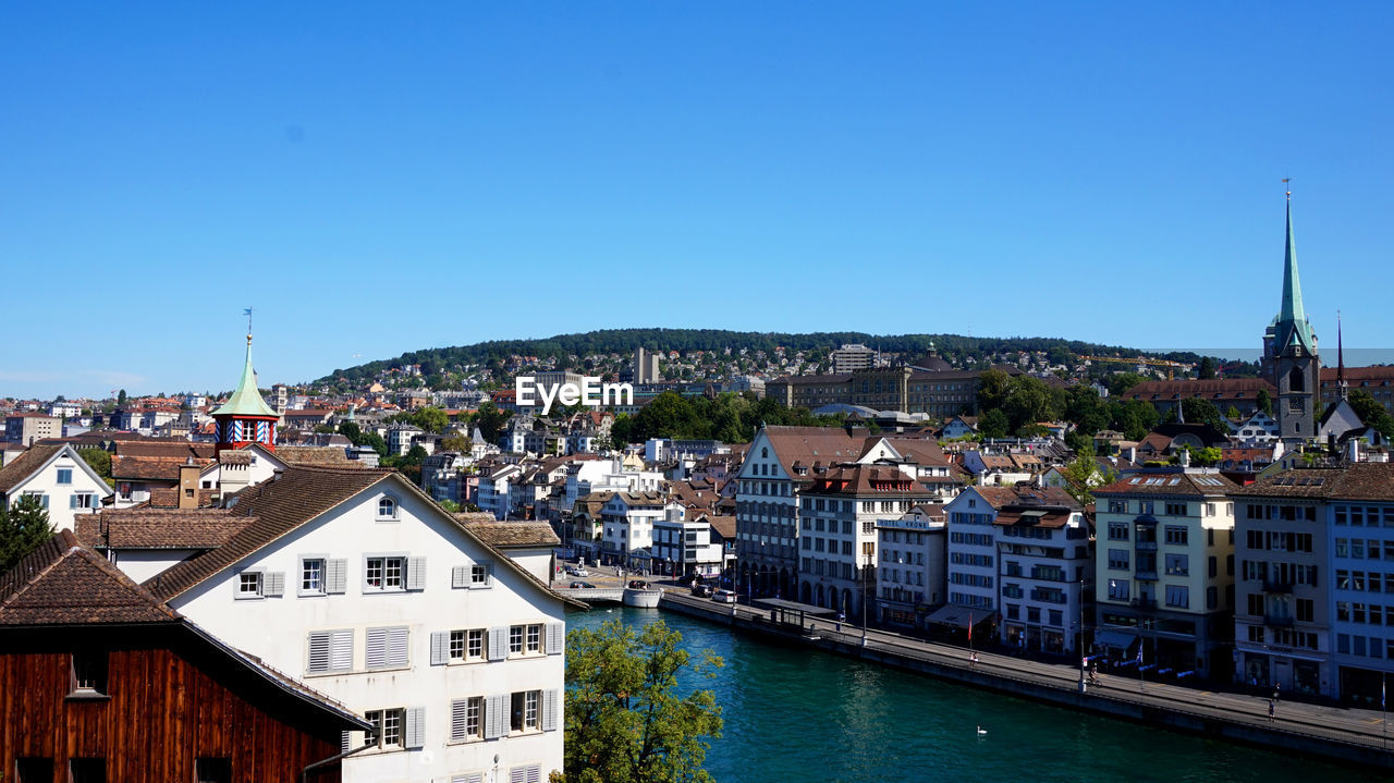 Buildings in city against clear blue sky