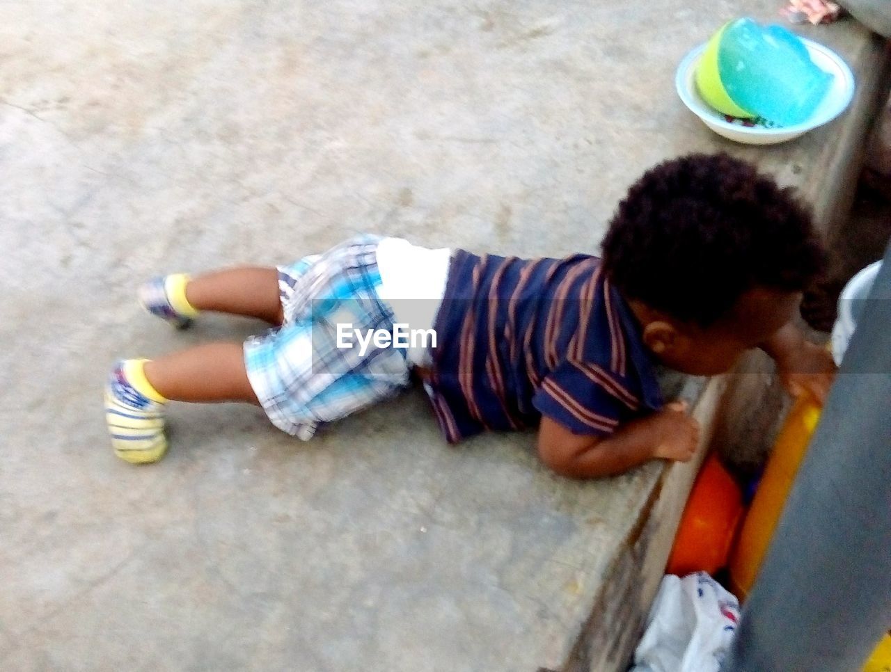 HIGH ANGLE VIEW OF BOY LYING ON COUCH HOLDING CAMERA