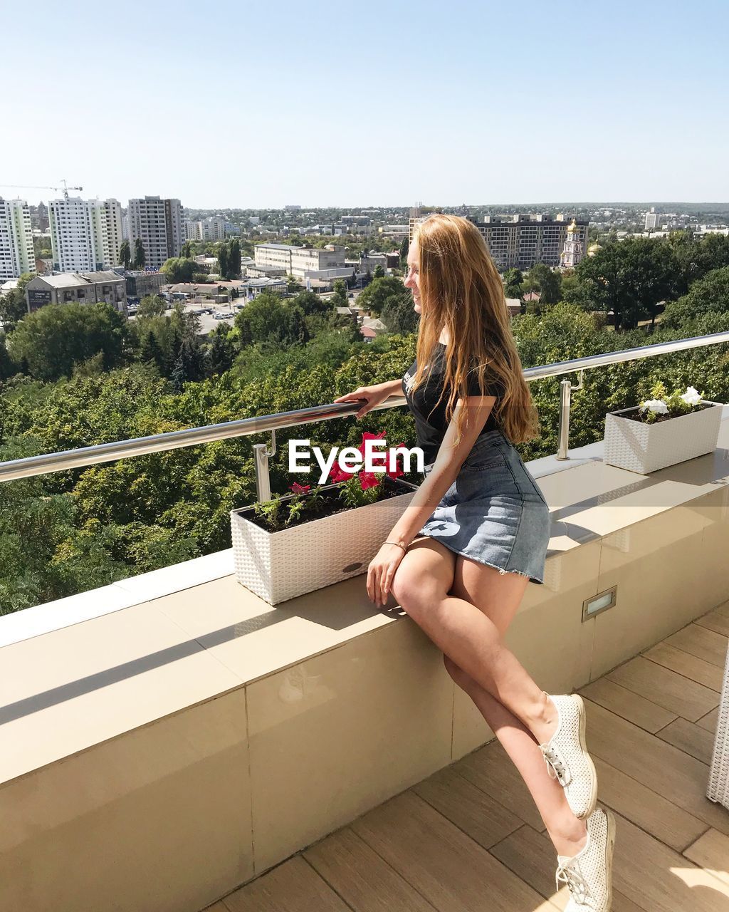 Full length of young woman sitting on building terrace in city