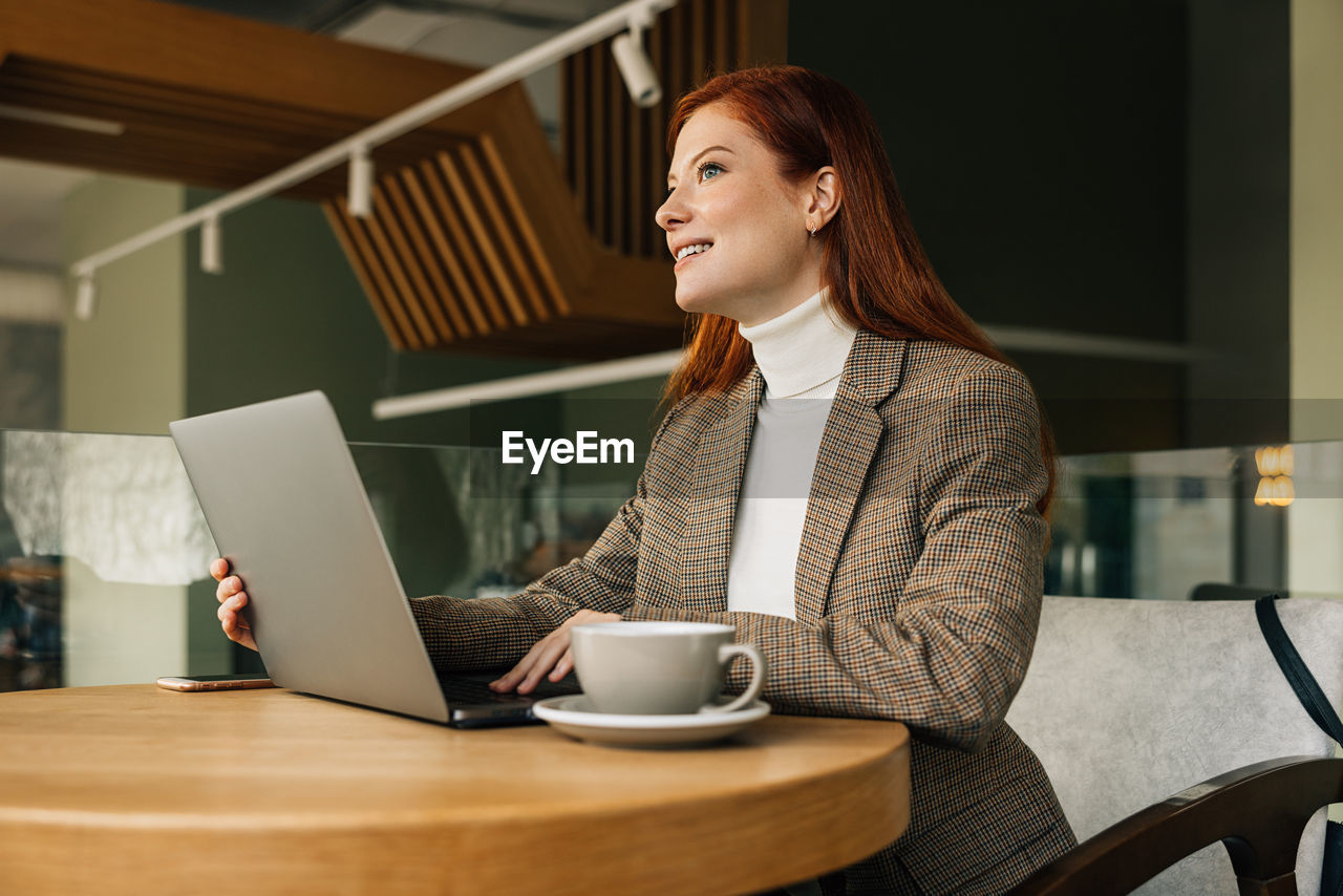 young woman using laptop while sitting on table
