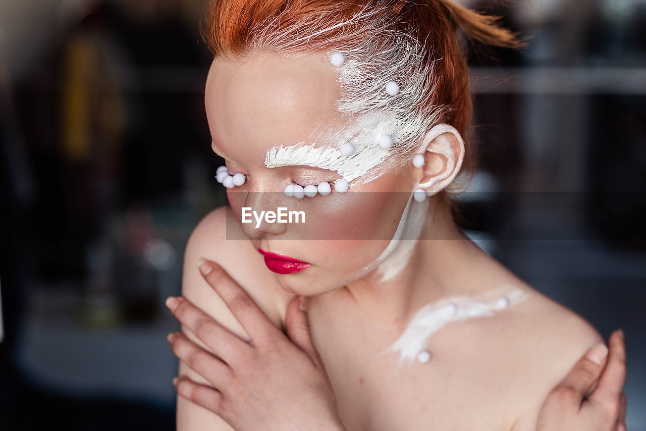 Close-up of young woman in white creative makeup 