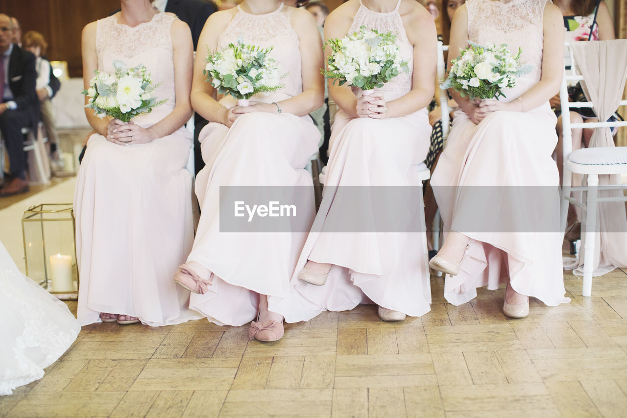 Low section of bridesmaids sitting on chairs