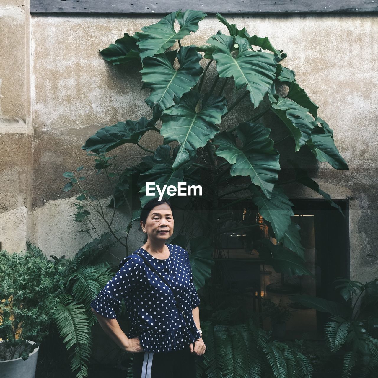 Portrait of senior woman standing against plants