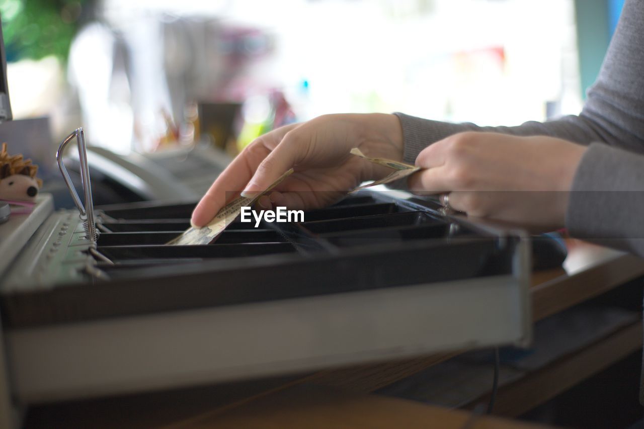 Cropped hands of woman putting money in box