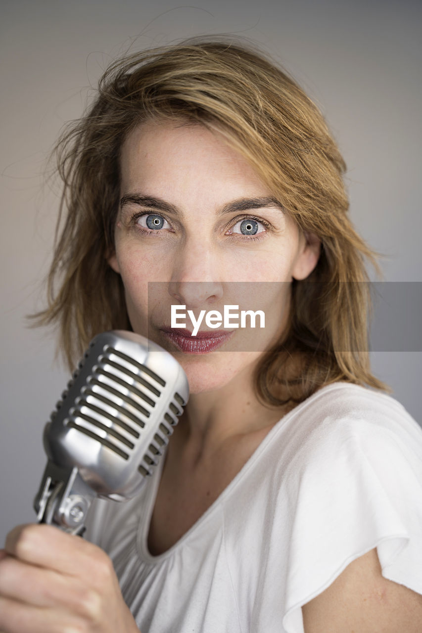 Portrait of woman singing song against colored background