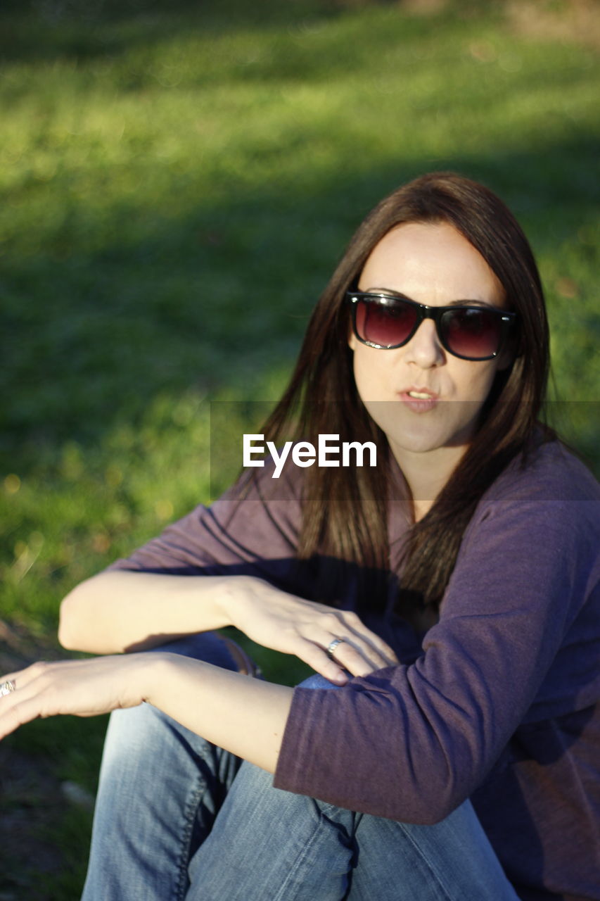 Beautiful young woman sitting on grass at park