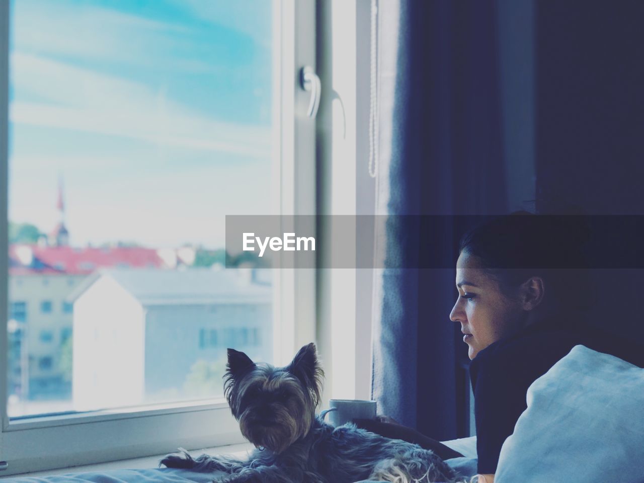 PORTRAIT OF WOMAN WITH CAT LOOKING THROUGH WINDOW
