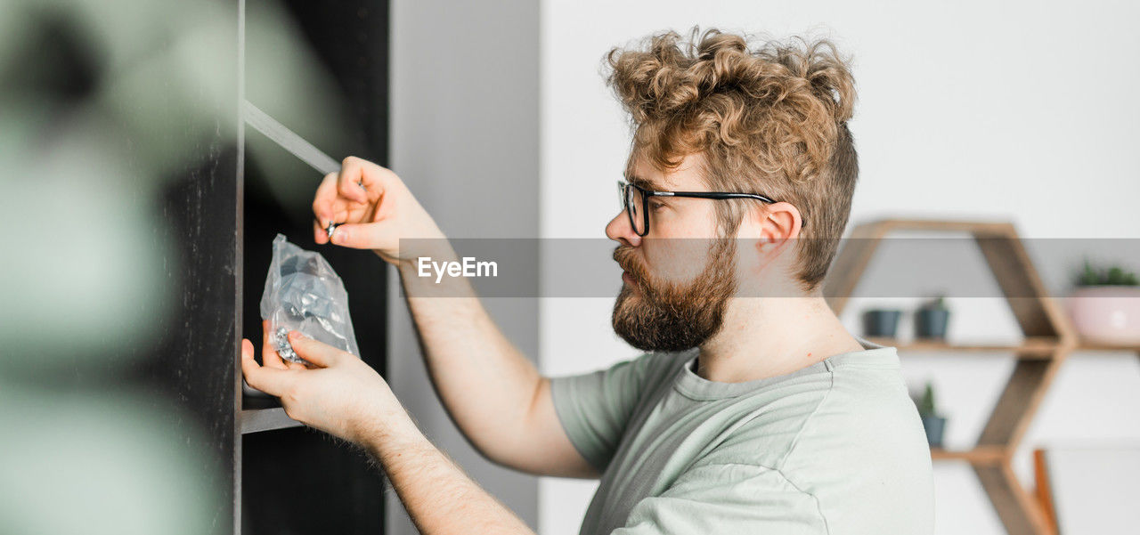 side view of man looking through window at home