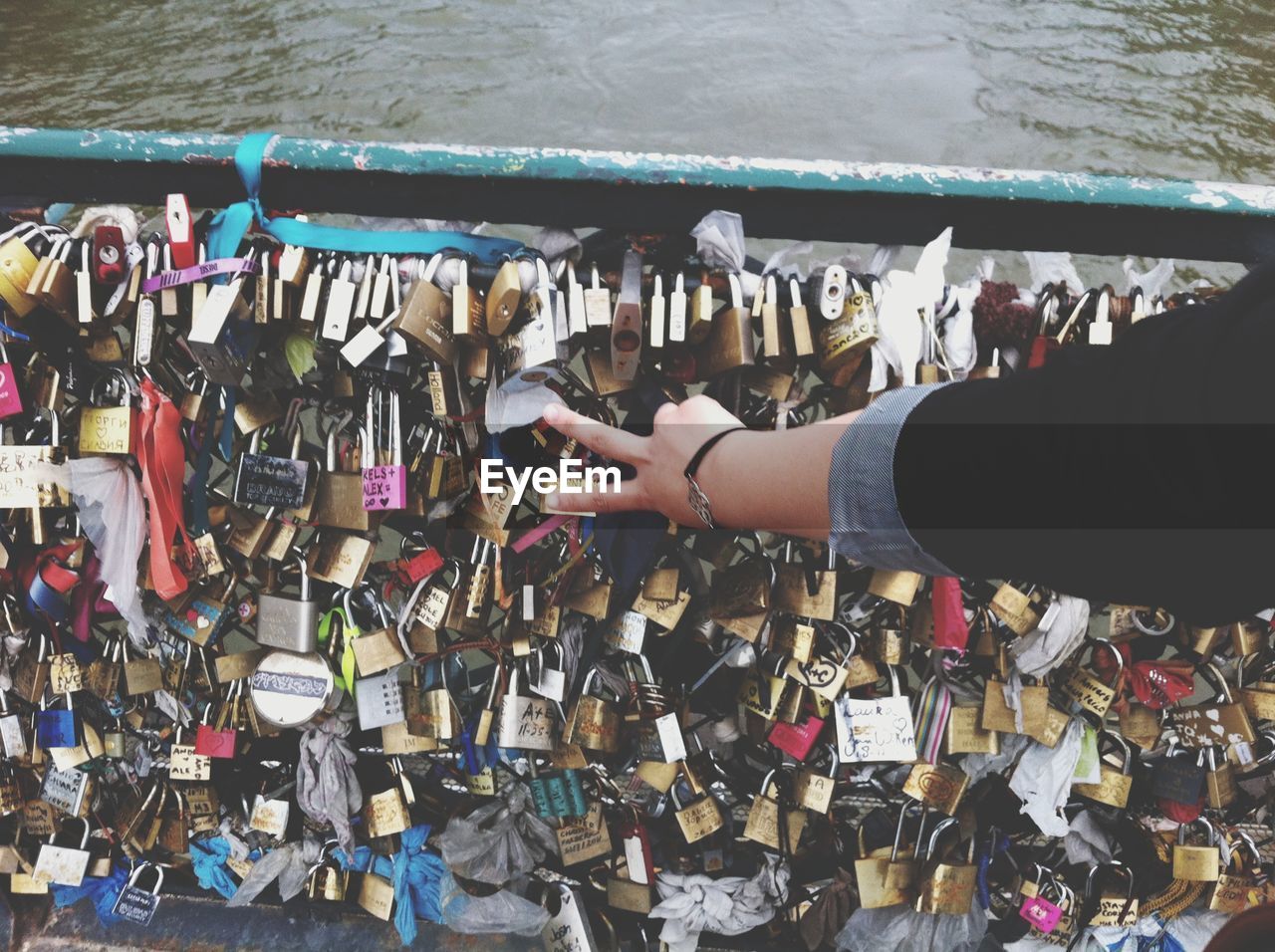 Close-up of padlocks hanging on bridge over river