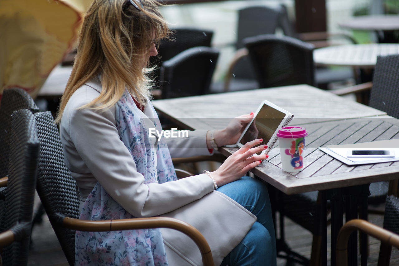 Woman using digital tablet while sitting at table