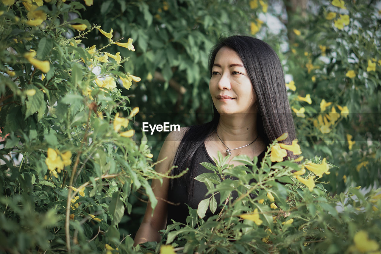 Young woman standing against plants