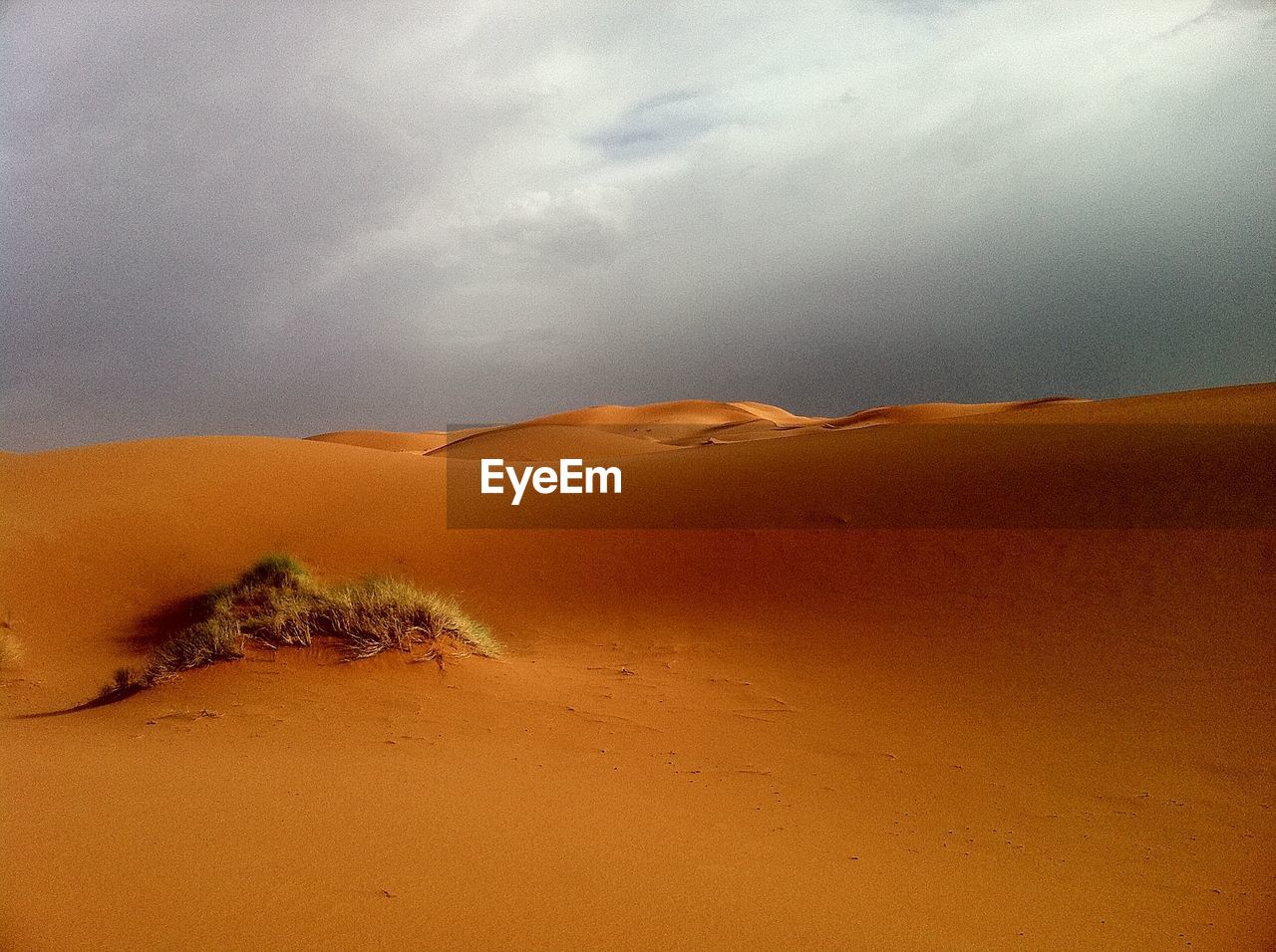 Scenic view of sand dunes against cloudy sky