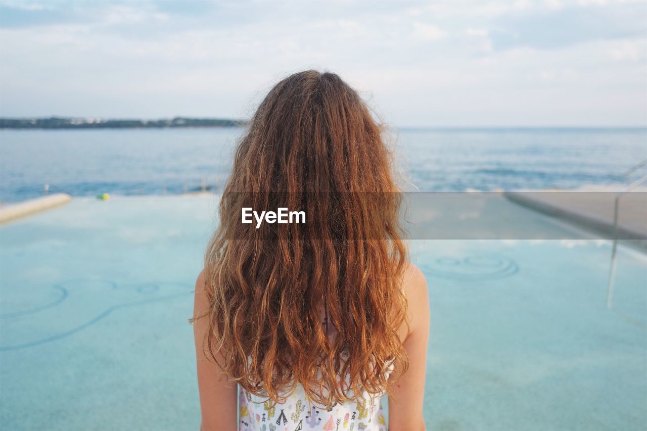 Rear view of woman standing against sea at beach