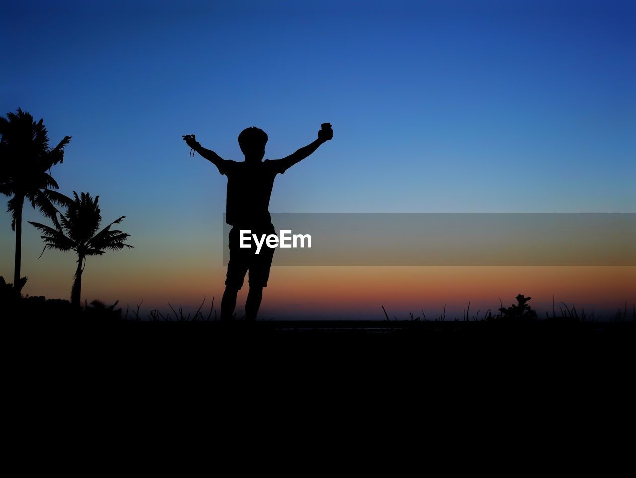 SILHOUETTE WOMAN STANDING ON FIELD AGAINST SKY DURING SUNSET