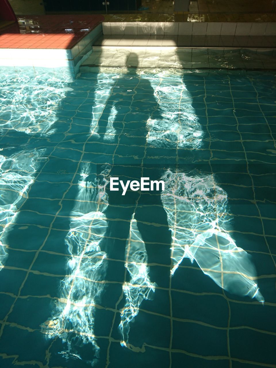 REFLECTION OF MAN SWIMMING IN POOL
