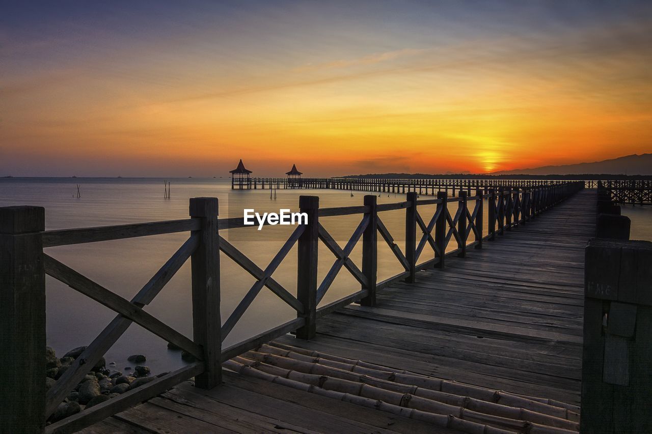 Pier over sea against sky during sunset