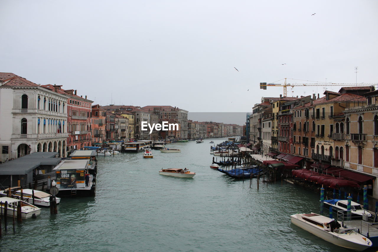 Boats moored on canal against buildings in city