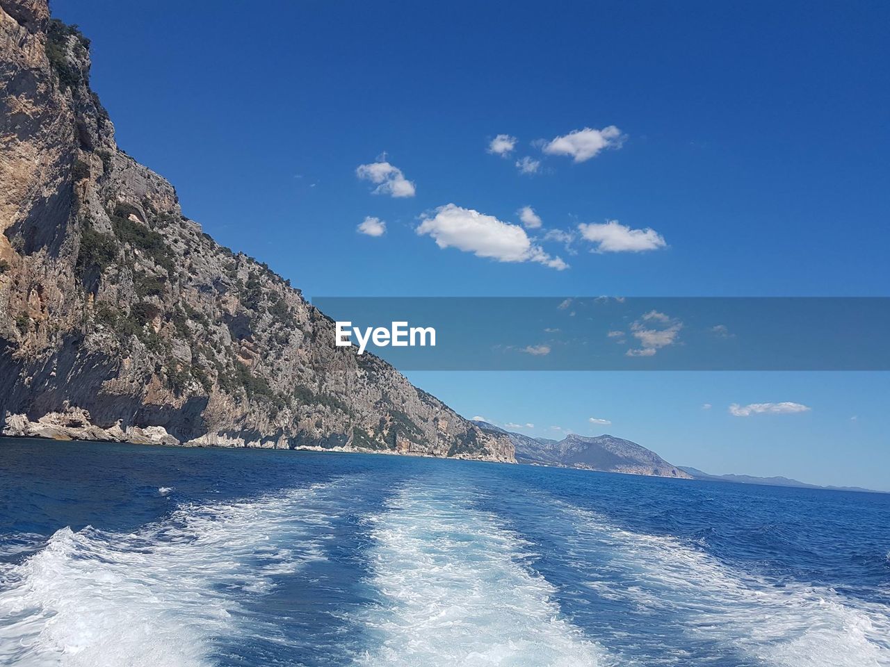 SCENIC VIEW OF SEA BY MOUNTAIN AGAINST BLUE SKY