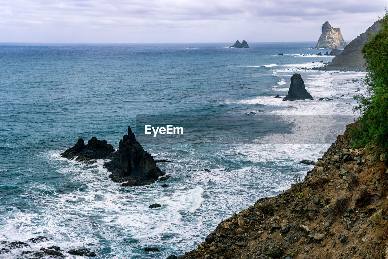 ROCK FORMATIONS ON SHORE AGAINST SKY