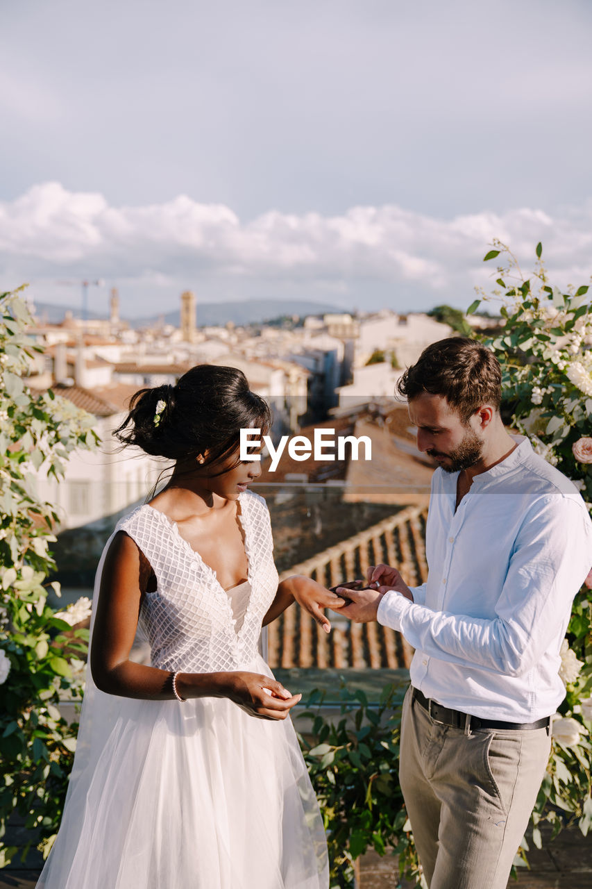 Couple standing by plants against sky