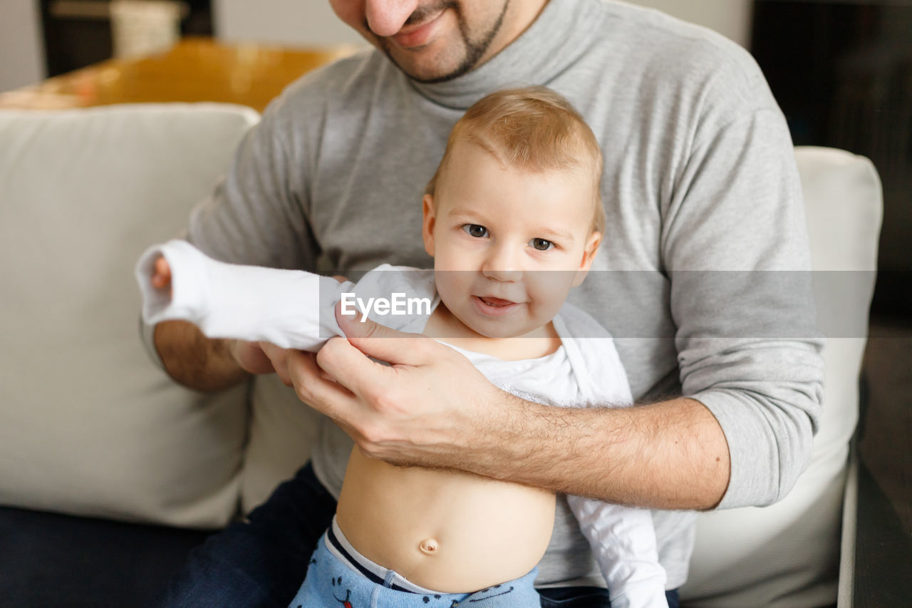Midsection of father with baby at home