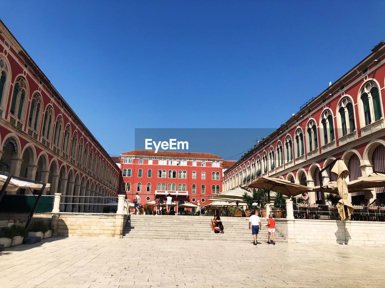 PEOPLE WALKING ON BUILDING AGAINST BLUE SKY