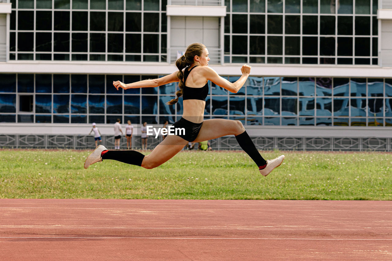 full length of young woman doing yoga on field