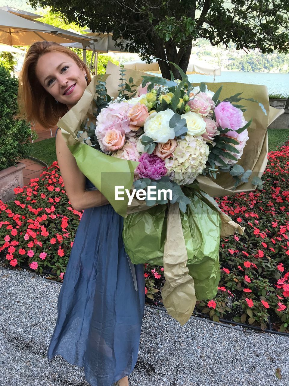 PORTRAIT OF SMILING WOMAN STANDING BY BOUQUET