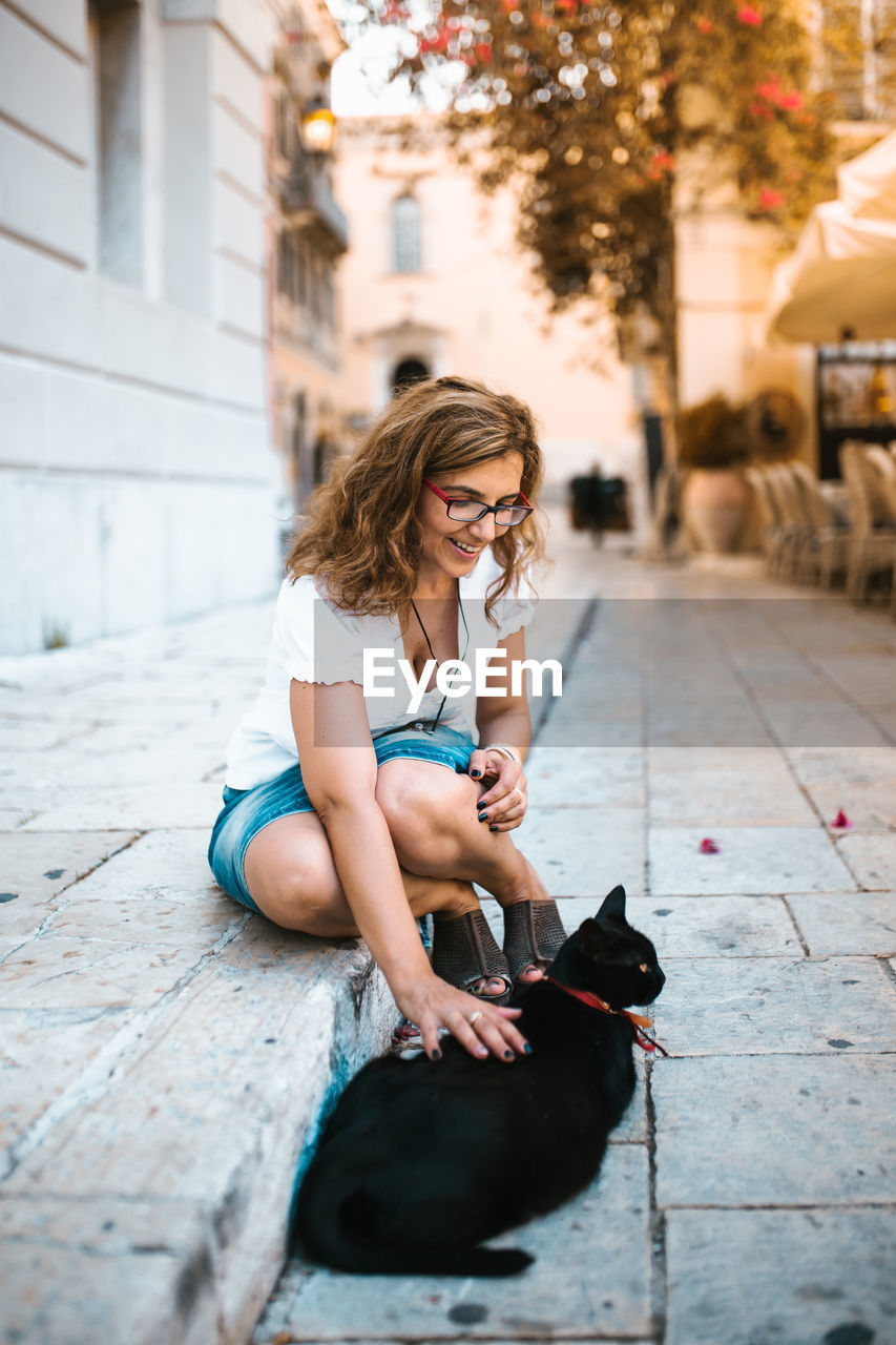 FULL LENGTH OF WOMAN SITTING IN CLOTHING WHILE RELAXING IN PARK