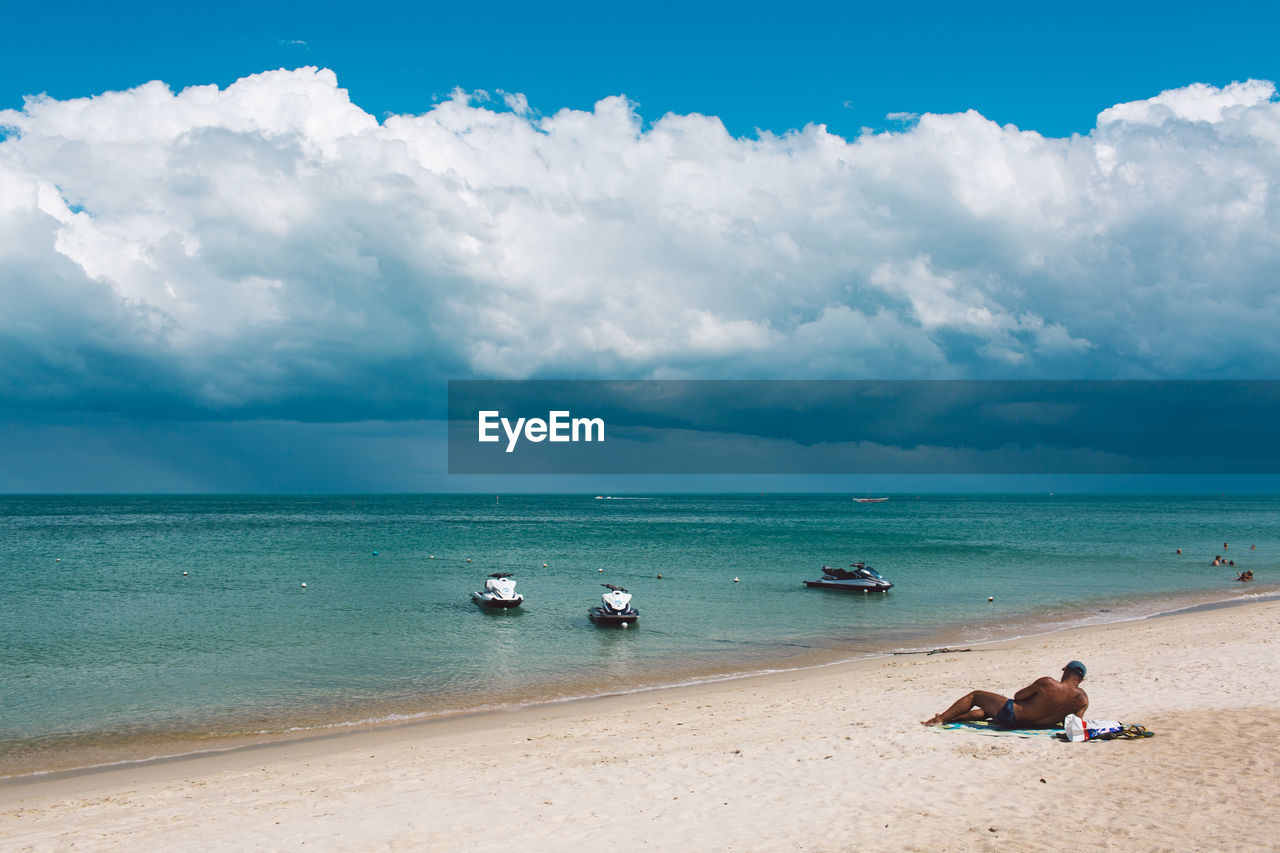 PEOPLE ENJOYING ON BEACH AGAINST SKY