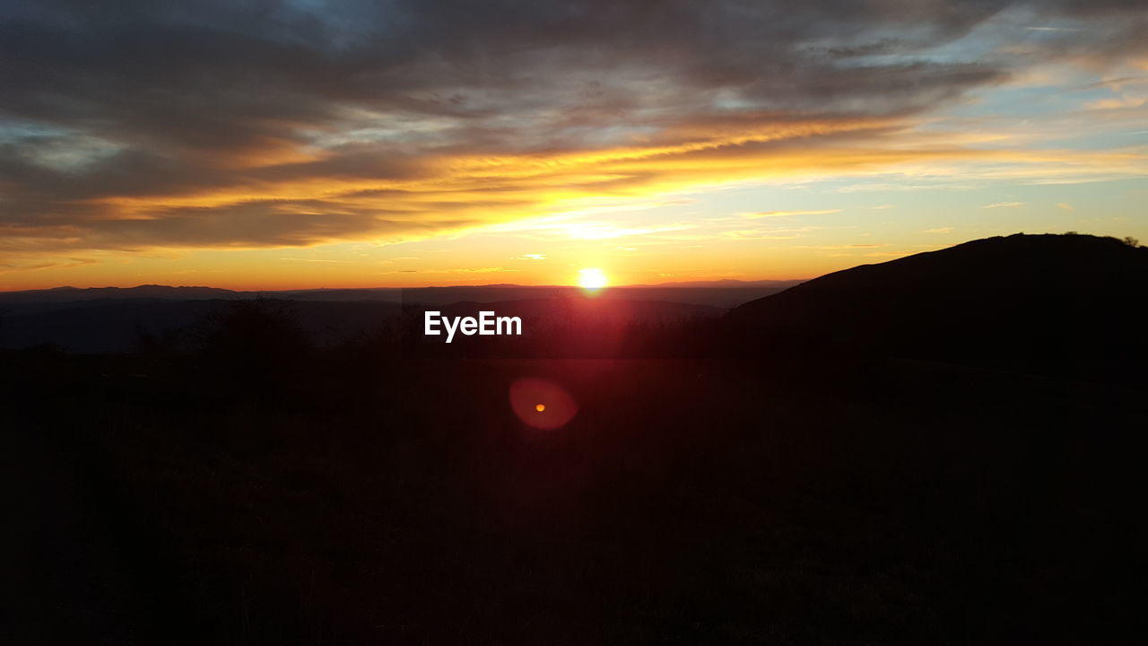 SCENIC VIEW OF SILHOUETTE MOUNTAIN AGAINST DRAMATIC SKY