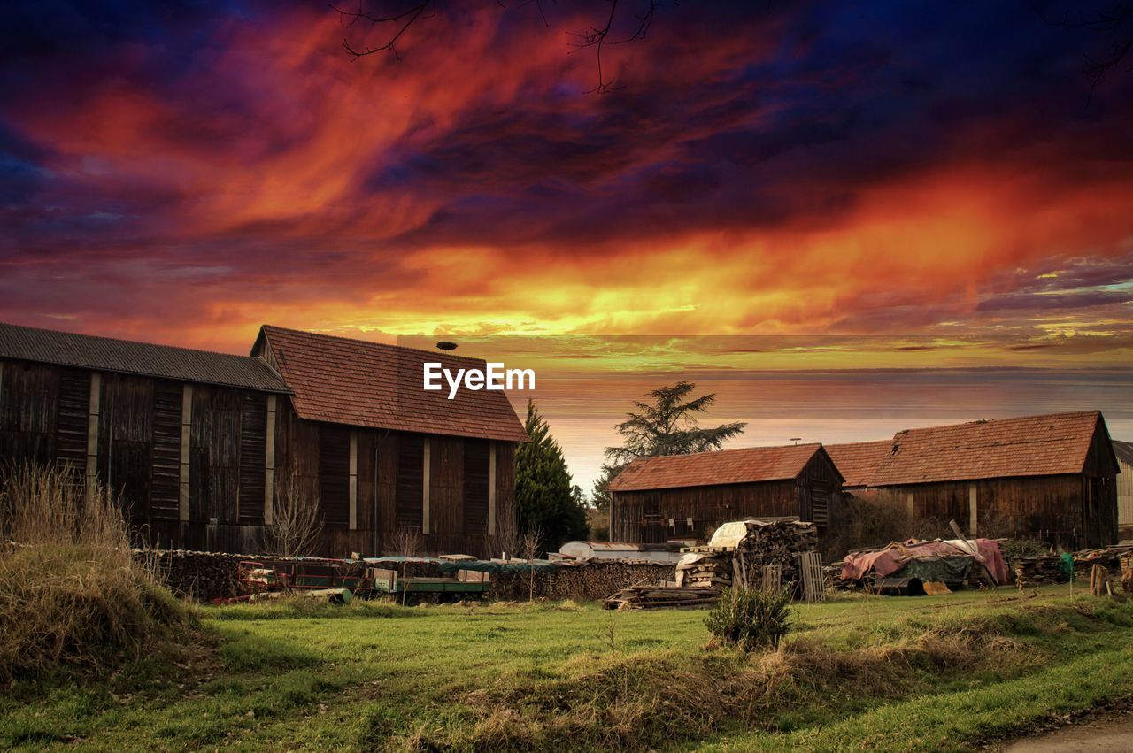 Houses on field against sky during sunset