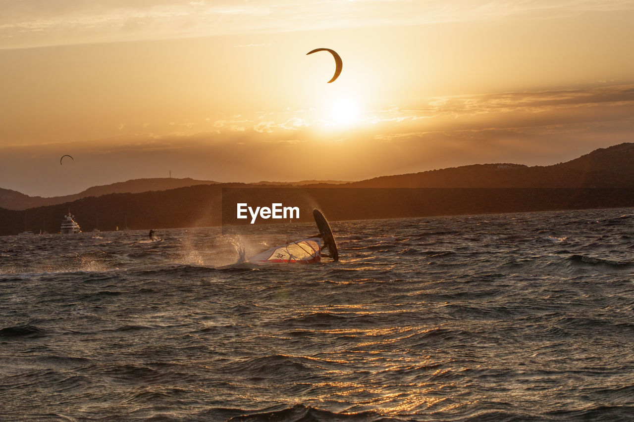 Scenic view of a kitesurfer in the sea against sky during sunset