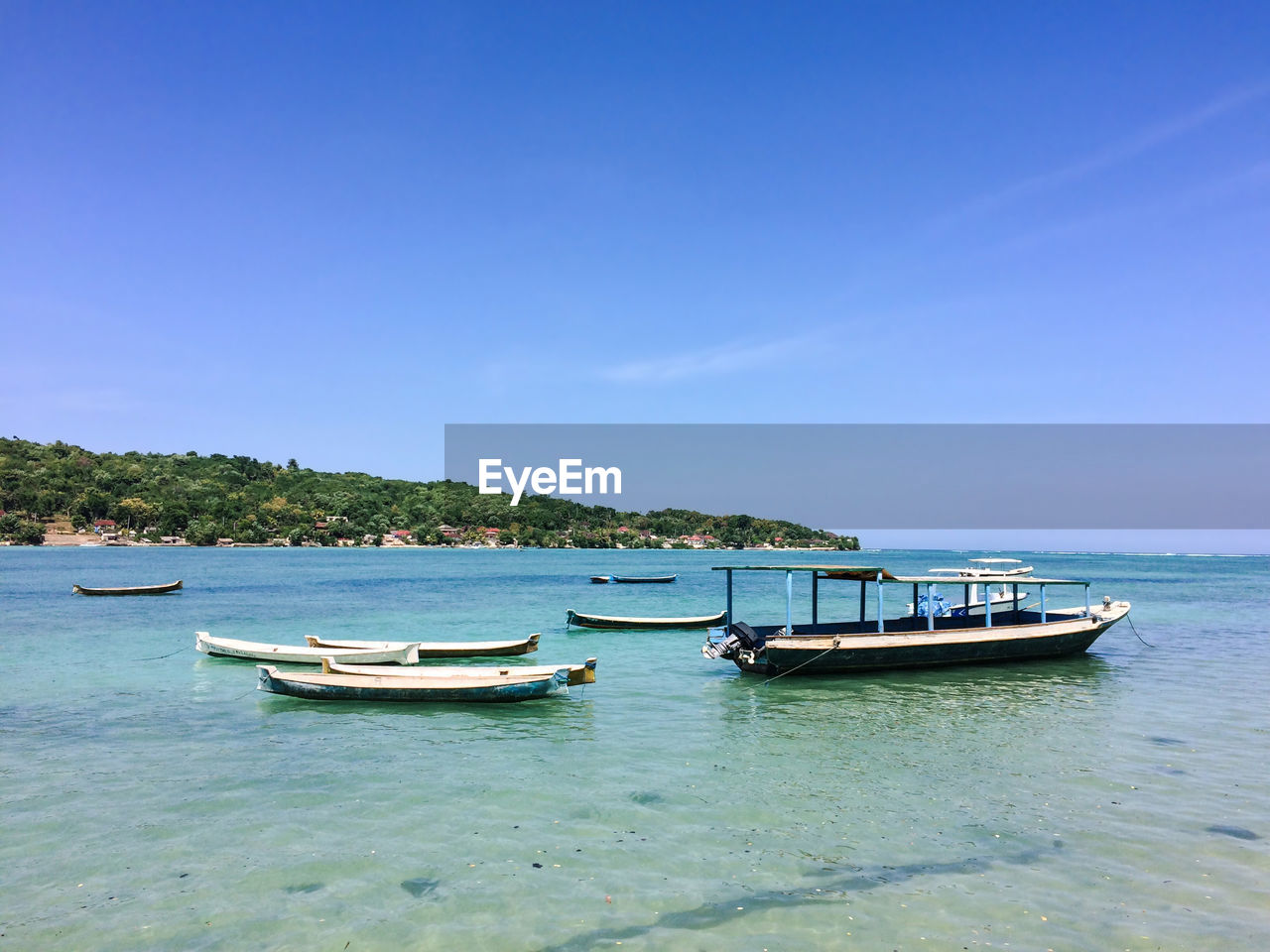 Boats anchored on sea against clear sky