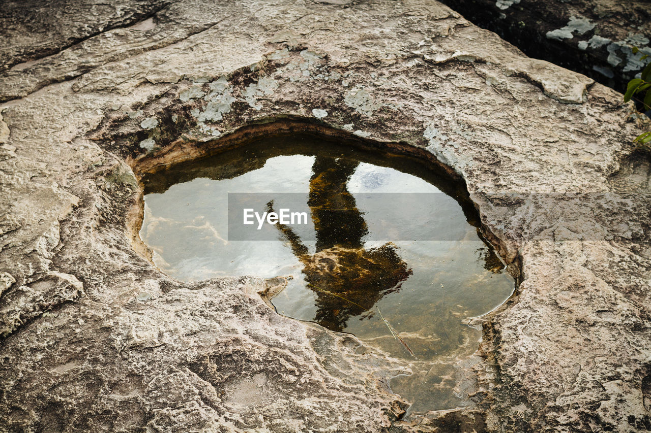 Reflection of man in water on rock formation