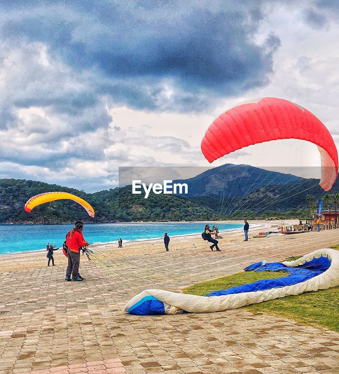 PEOPLE FLYING BEACH AGAINST SKY