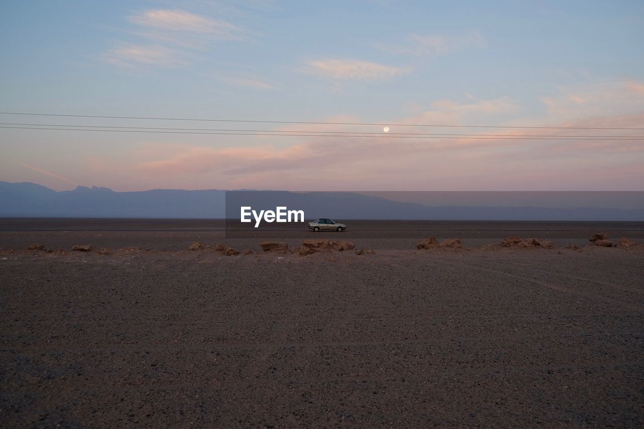 SCENIC VIEW OF BEACH AGAINST SKY AT SUNSET