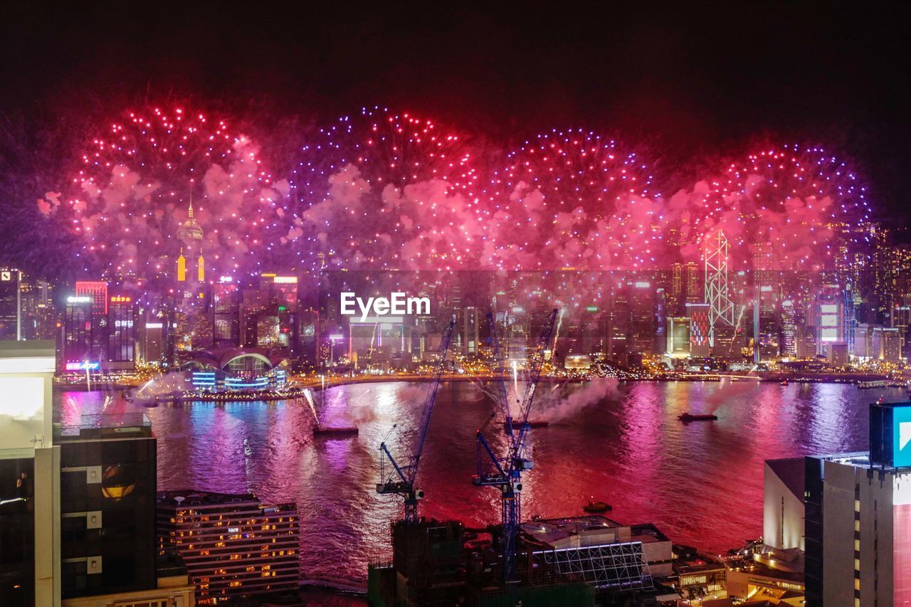 Firework display over river in city at night