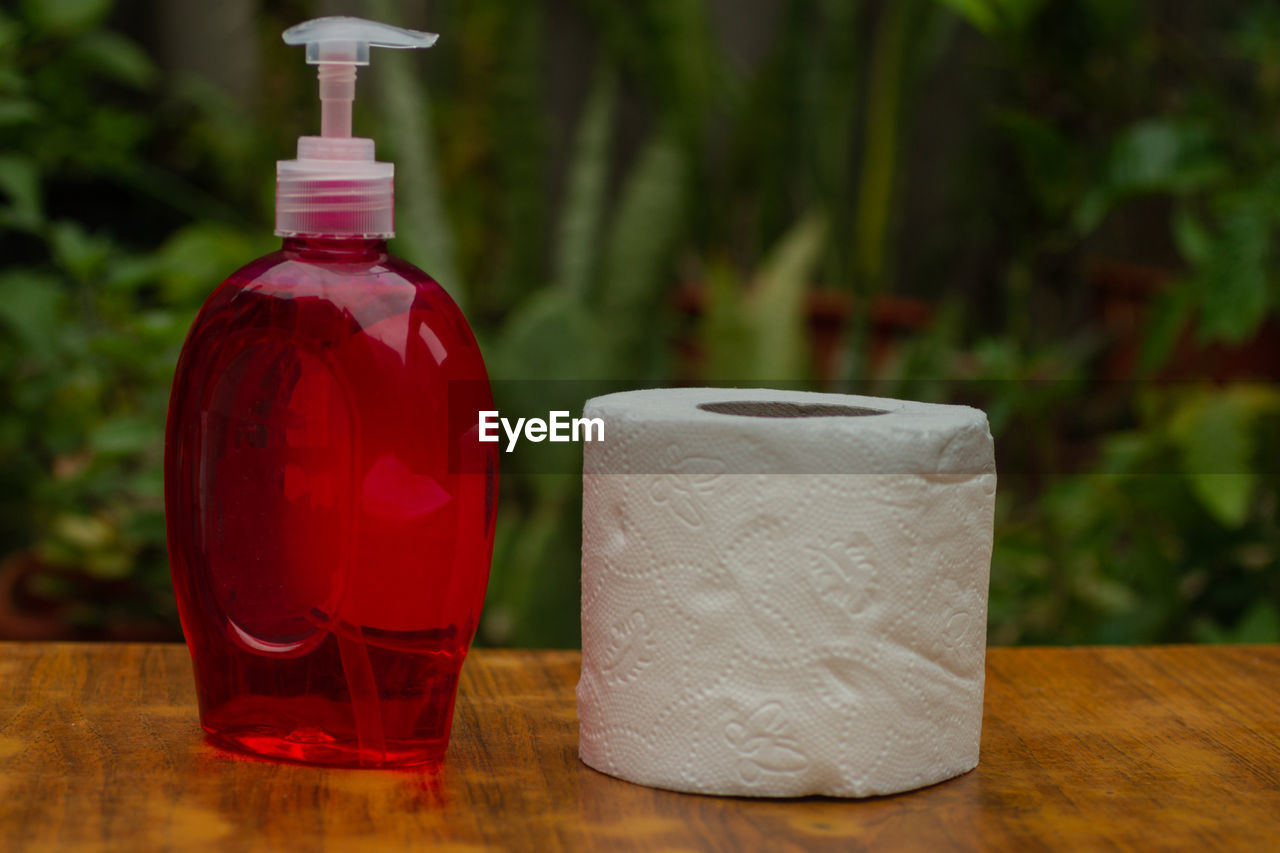 Close-up of antiseptic bottler and toilet paper on table