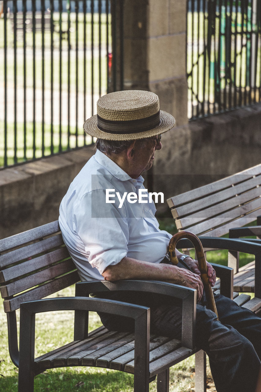 MAN SITTING ON BENCH AGAINST WALL