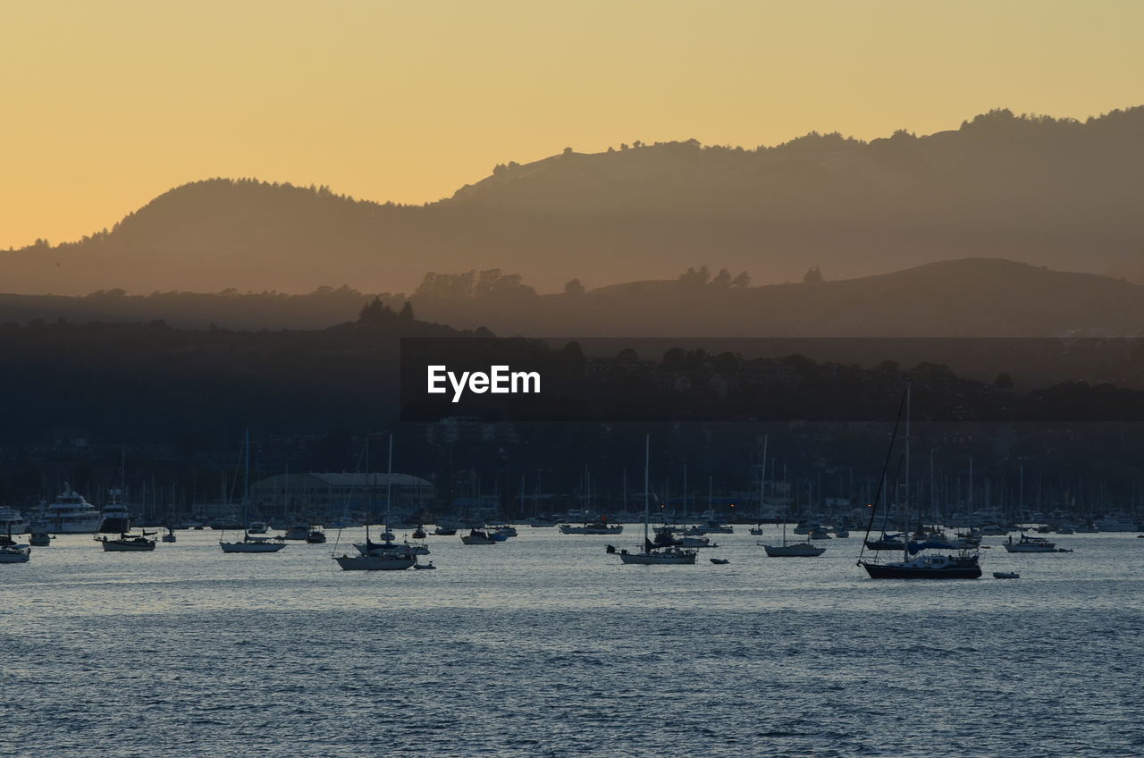 Silhouette sailboats in lake against sky during sunset