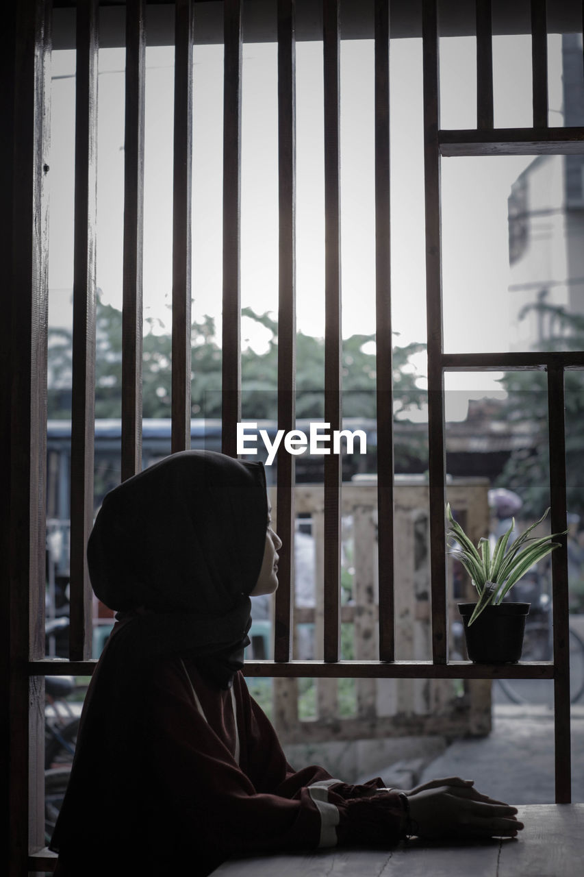 Side view of woman looking through window in cafe