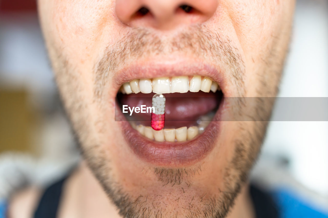 Close-up of man eating a pill 